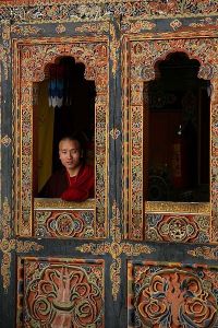 Bhutanese Buddhist monk looking out the window of a monastery.
